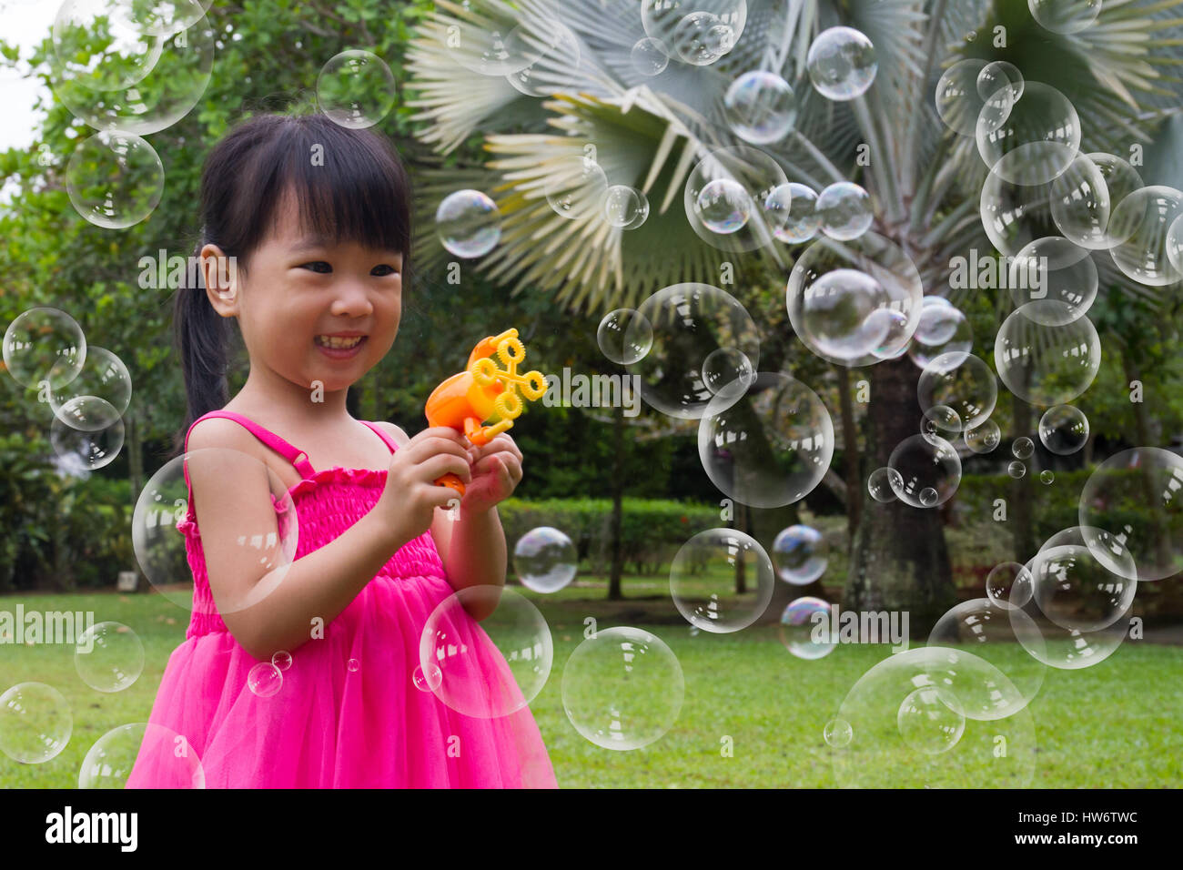 Asian Little Chinese Girls Shooting Bubbles from Bubble Blower in the Park Stock Photo