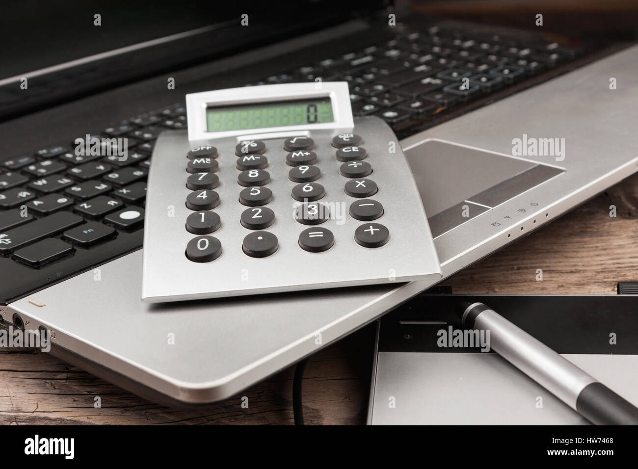 Laptop with a calculator and a graphic tablet on a wooden table. View of the desktop. Stock Photo
