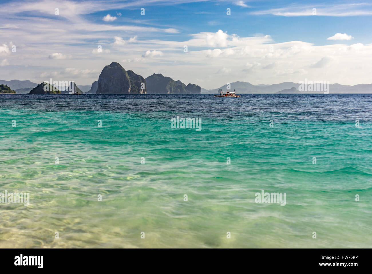 Small islands sat on the horizon taken at a low angle over an empty calm tropical sea  with depth of field. Stock Photo