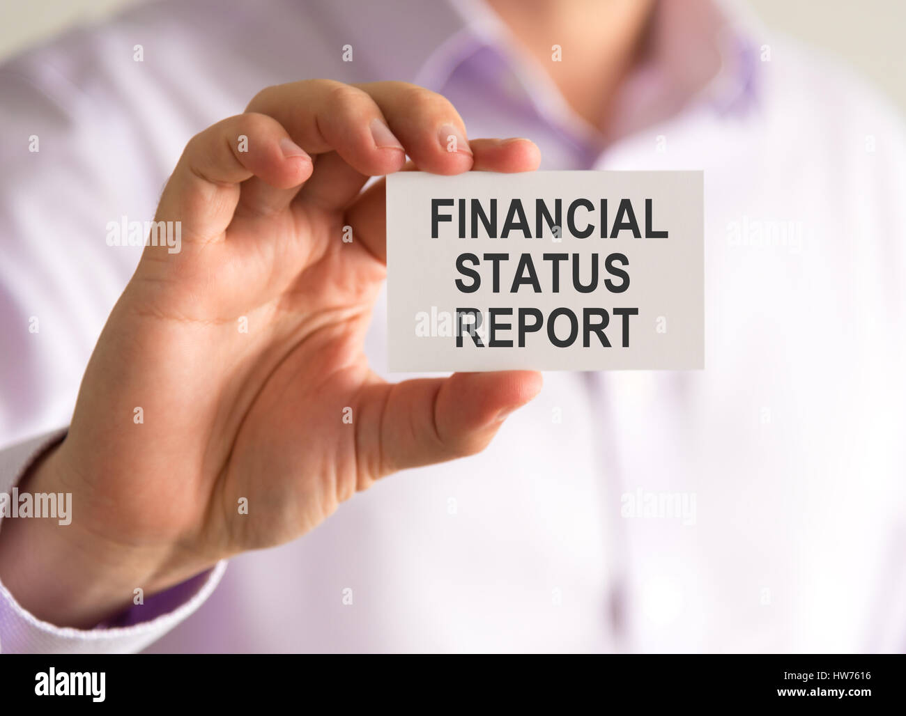 Closeup on businessman holding a card with FINANCIAL STATUS REPORT message, business concept image with soft focus background Stock Photo