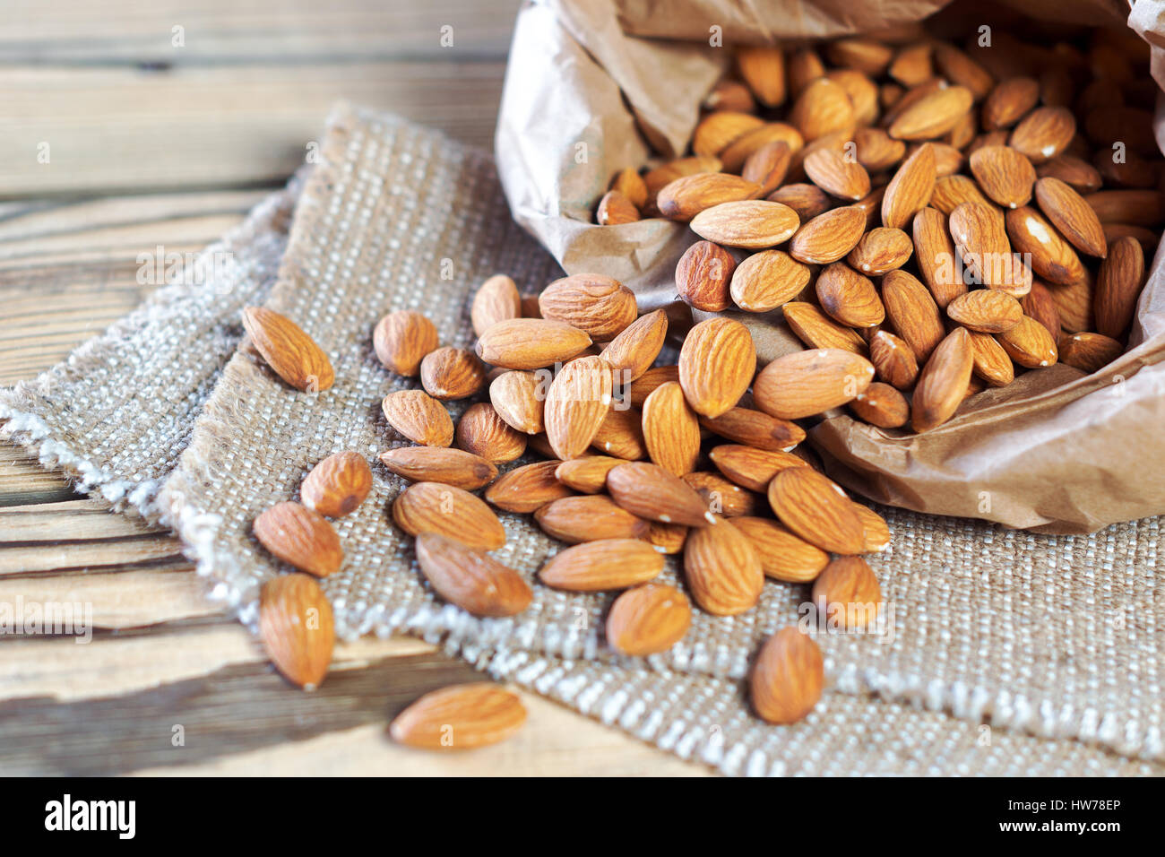 Almonds, pour out on wooden table out of a paper bag. Healthy eating. Stock Photo