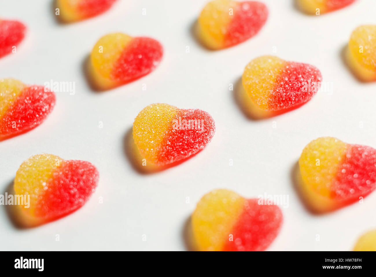 Sweet bright candies in the form of hearts on a white background. Shallow DOF, soft focus. Stock Photo