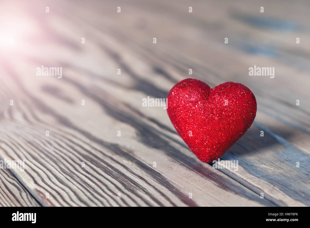 Red heart with glitter on wood. St. Valentine's Day. Shallow DOF, soft focus. With light effects. Stock Photo