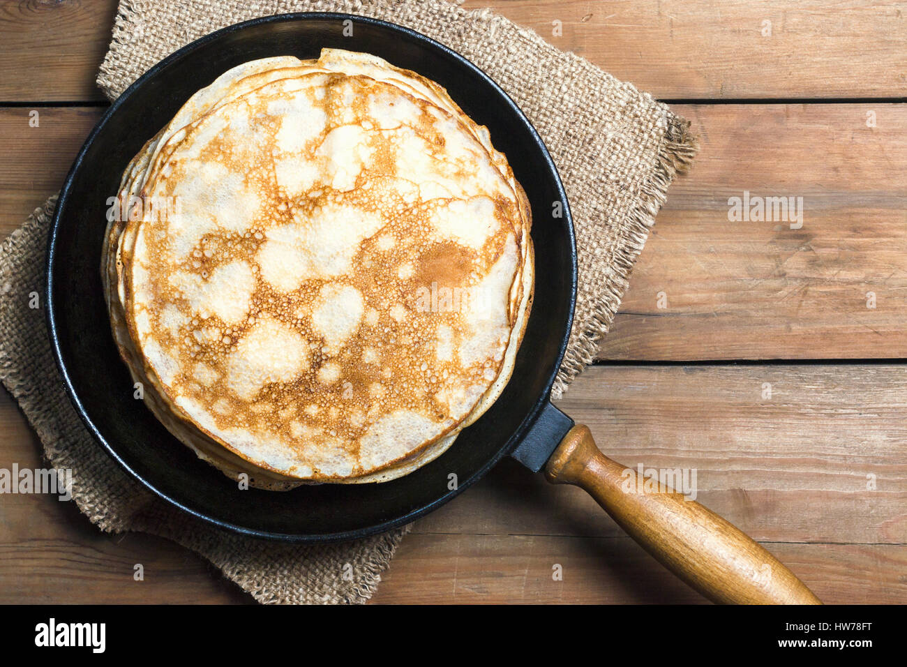 Stack of pancakes on a cast-iron frying pan on a wooden table. Top view. Flat lay Stock Photo