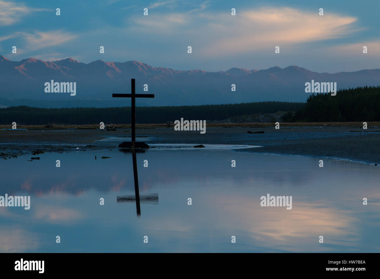 Dark cross in a drying up river way. With some mountain ranges in the background. Stock Photo