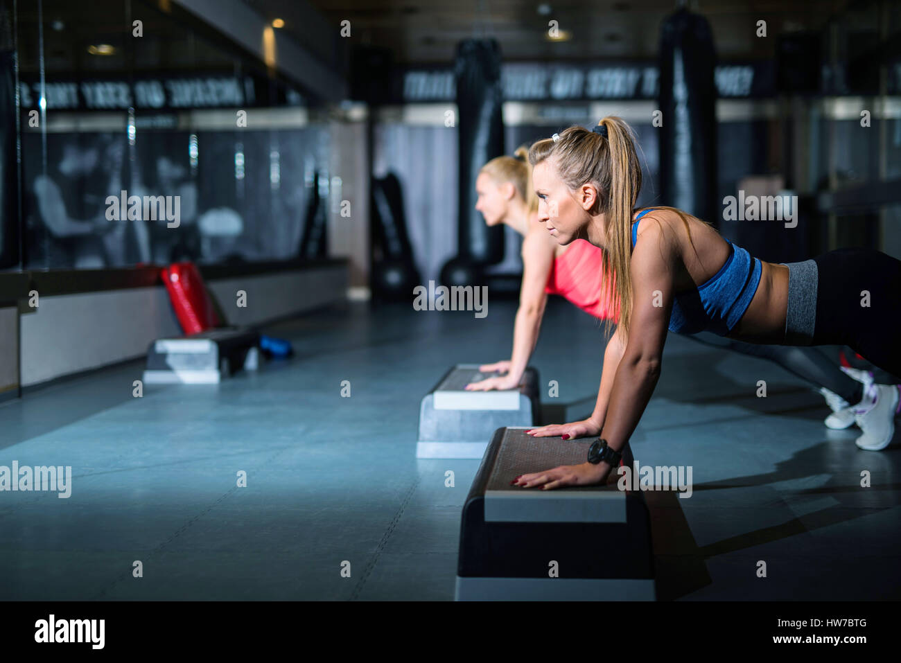 Two young athletic women doing push ups side view Stock Photo