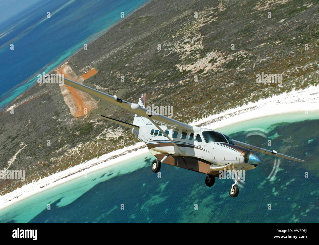 Aerial view of Cessna 208 Caravan aircraft leaving dirt airstrip on an island Stock Photo
