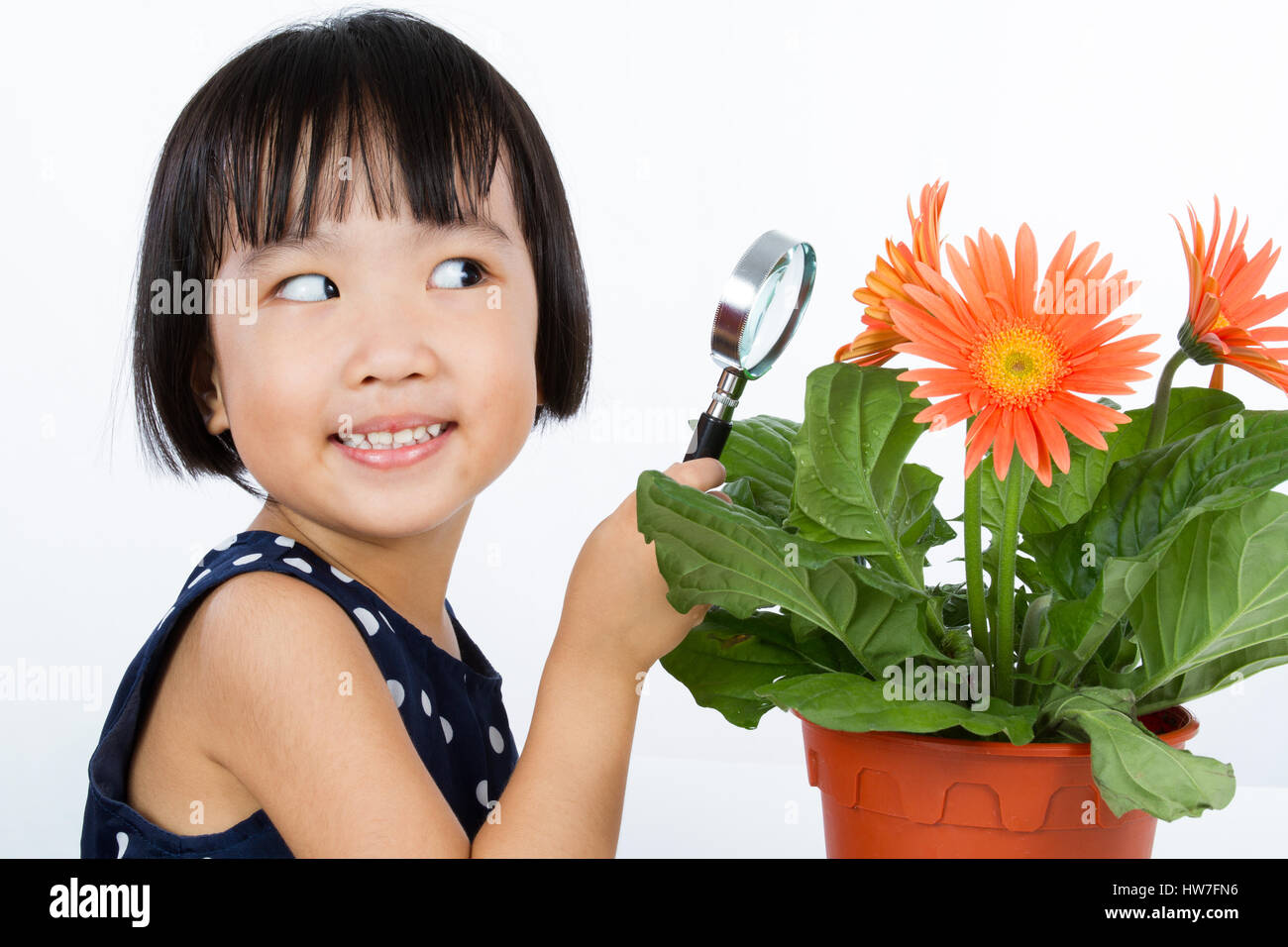 Asian Little Chinese Girl Looking at Flower through a Magnifying Glass