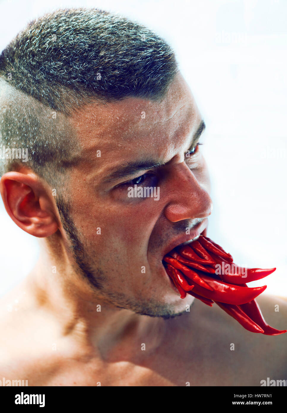 desperate young man with a lot of chilli pepper in mouth, lookin Stock Photo