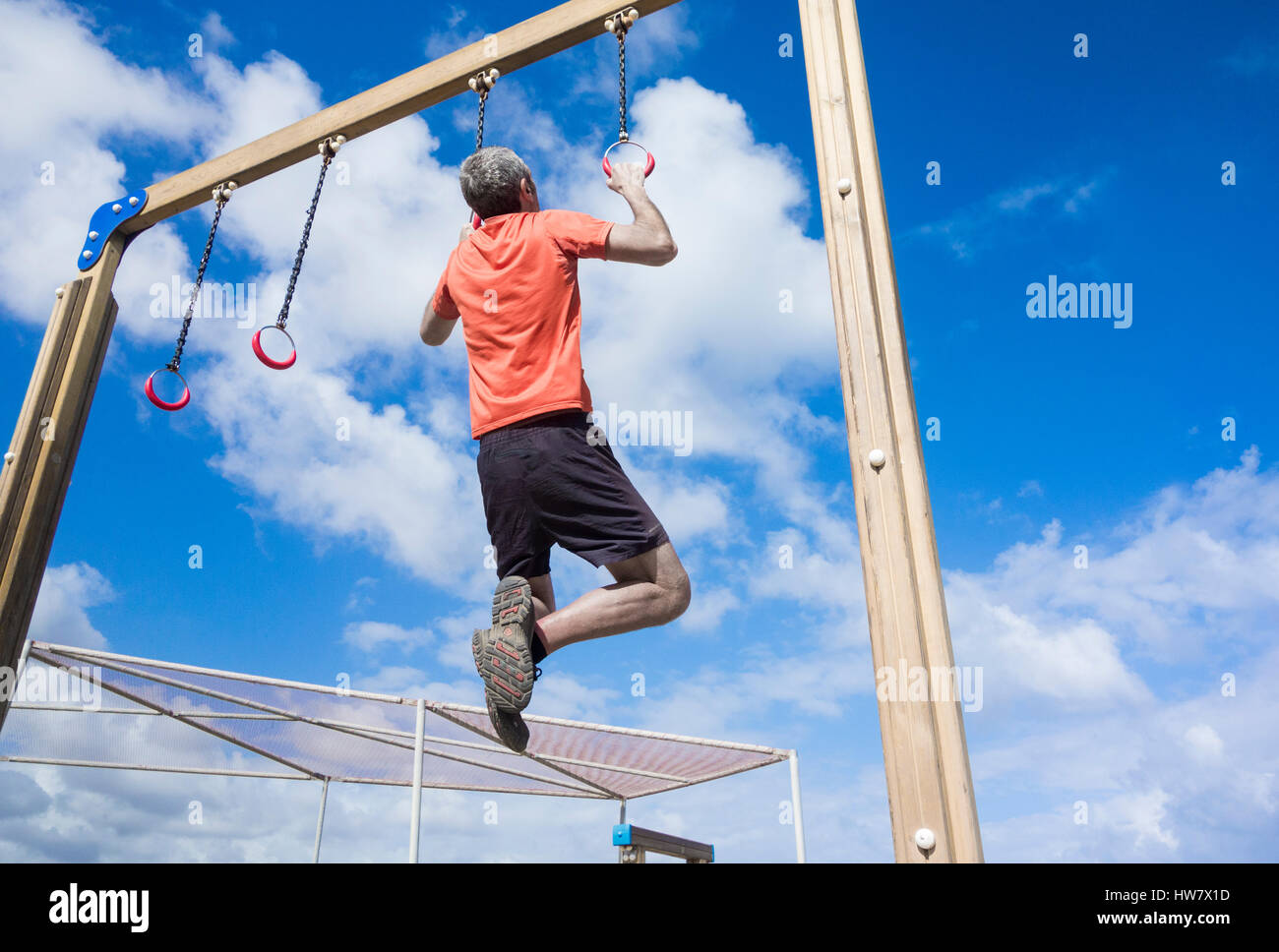 Mature man performing pull ups on rings in park Stock Photo