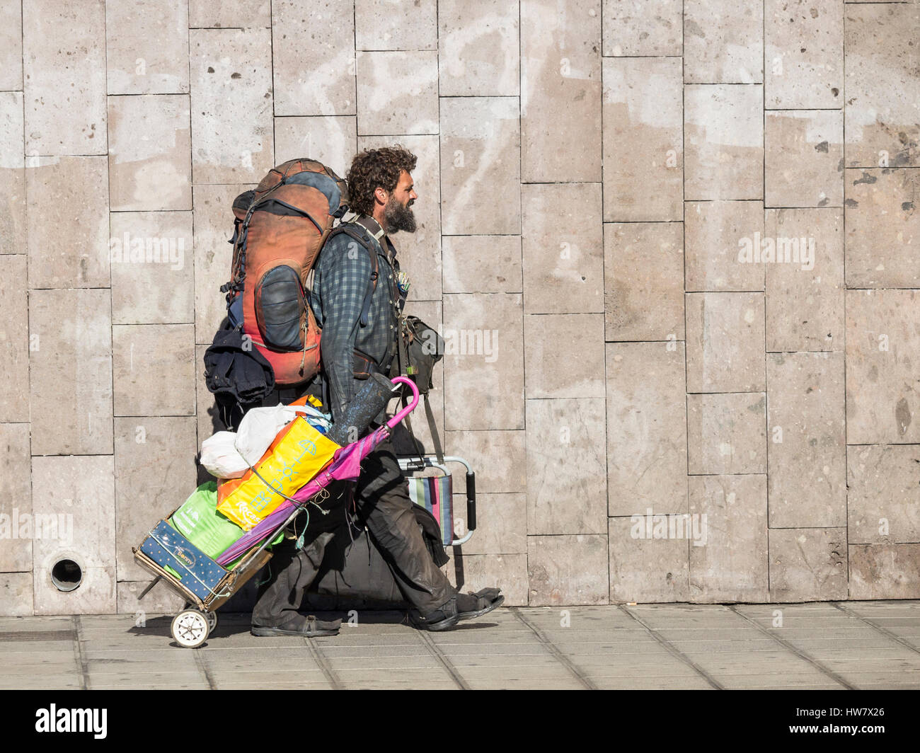 Homeless man in dirty clothes with large rucksack. Stock Photo