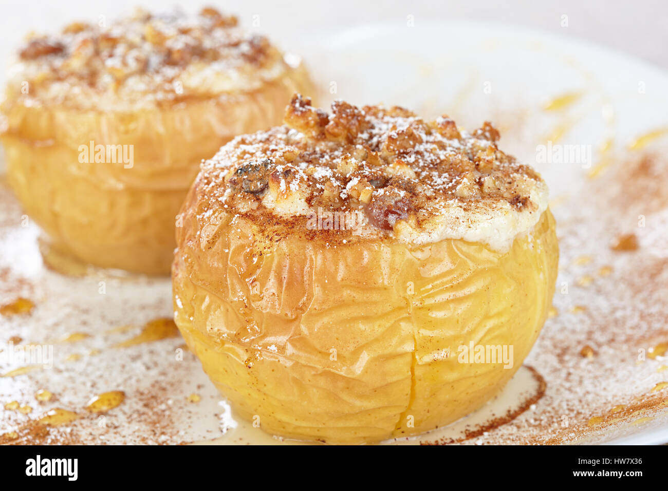 Apples baked with cottage cheese and raisins, decorated with nuts, cinnamon and powdered sugar Stock Photo