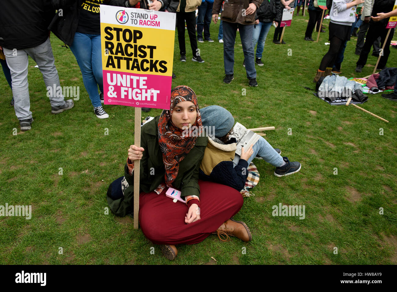 Muslim woman Anti-racism protester is holding a placard reading: 'Stop Racist Attacks, Unite & Fight' during the UN Anti-Racism Day in London, UK. Stock Photo