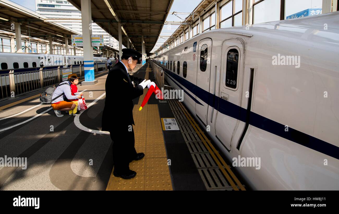Japan, Honshu island, Hiroshima, Train assistent observes the Shinkansen's stop at Hiroshima station looking at his watch, Trains in Japan leave on the second, Stock Photo