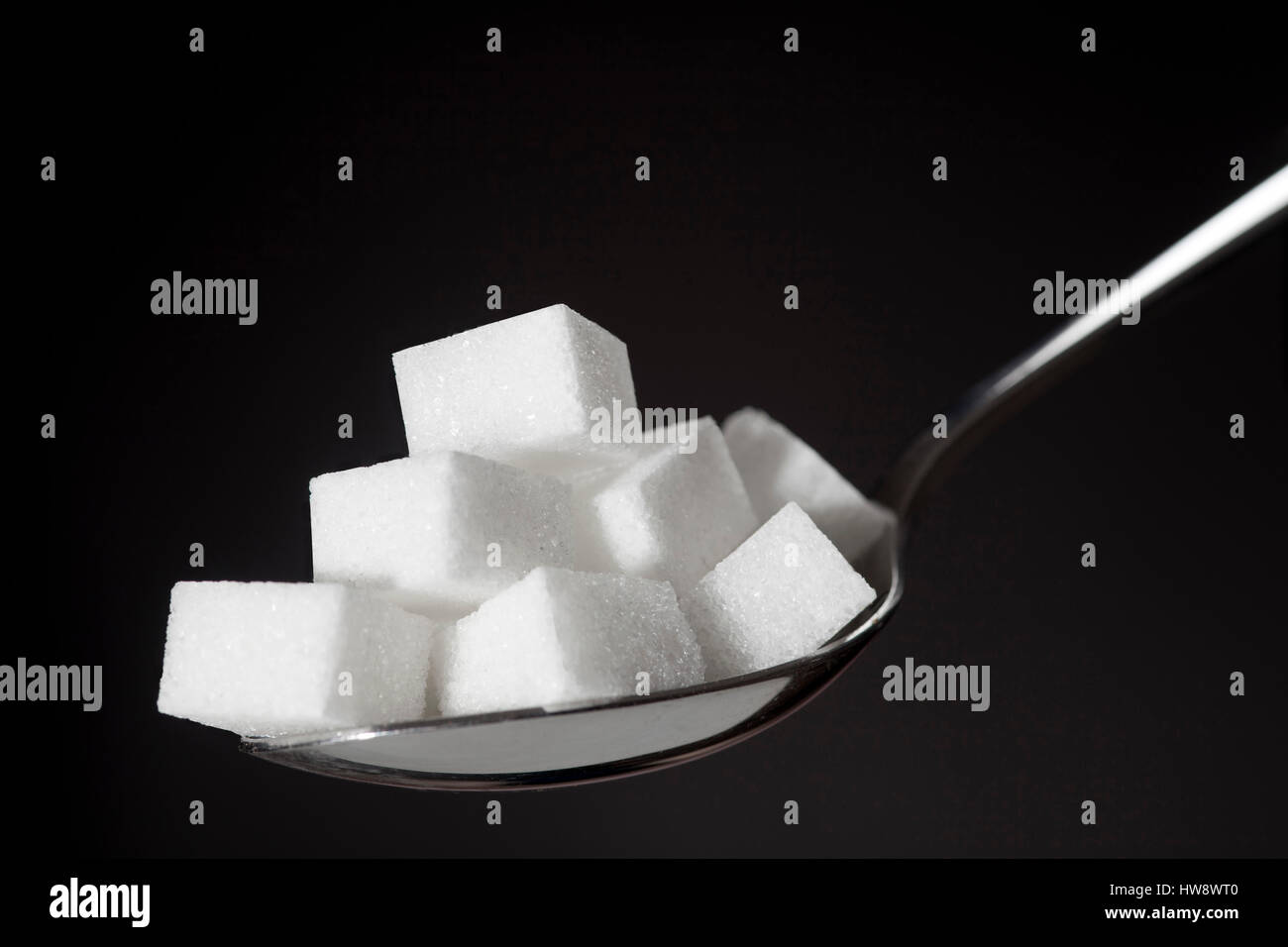 teaspoon with pile of lump white sugar on black background Stock Photo ...
