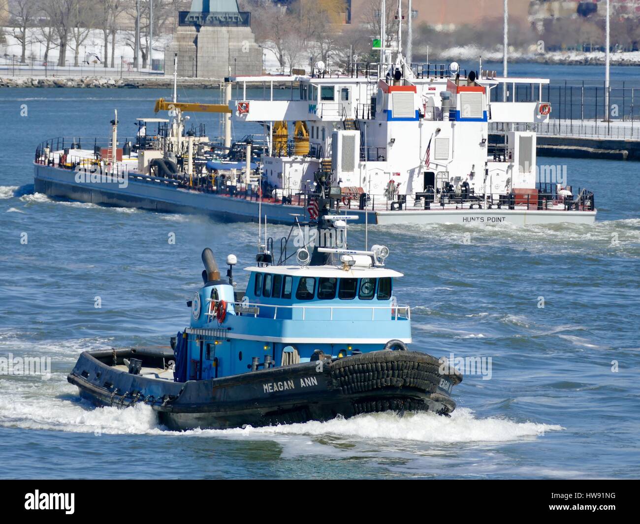 Light blue tugboat passing barge on the East River, New York, New York, USA Stock Photo