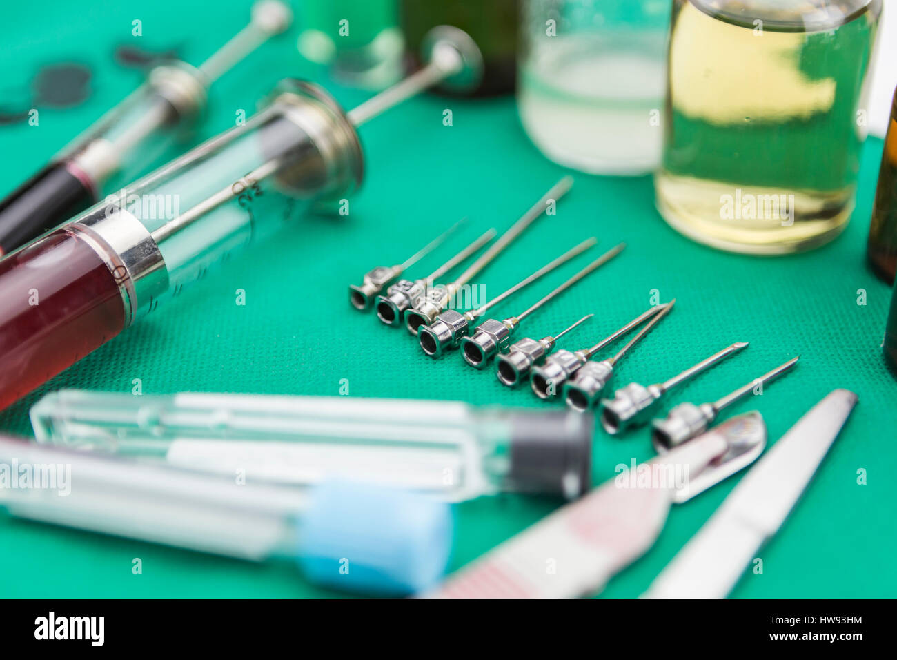 Needles metal of various sizes next to syringes in a table of op Stock Photo