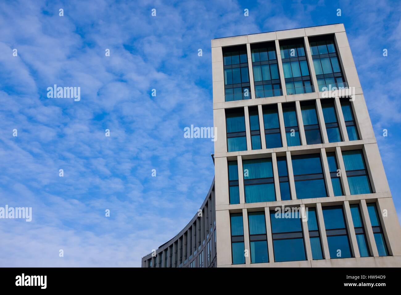 Blue rectangular windows in modern building in Liverpool contrasted against wispy cloud in blue sky Stock Photo