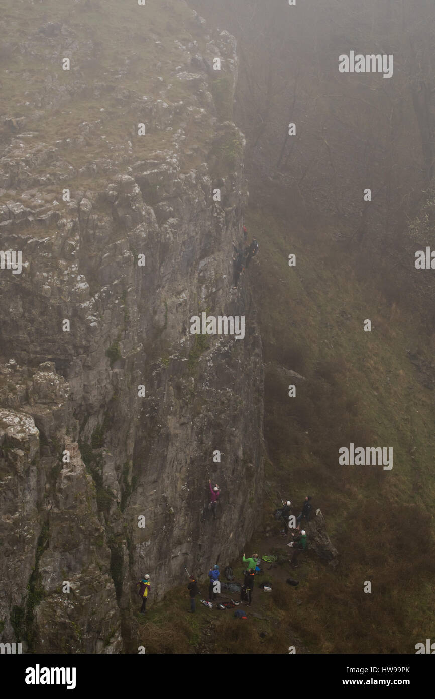 Group of rock climbers in fog at Cheddar Gorge ascend cliff in Somerset, UK, in one of Britain's most impressive areas of natural beauty Stock Photo
