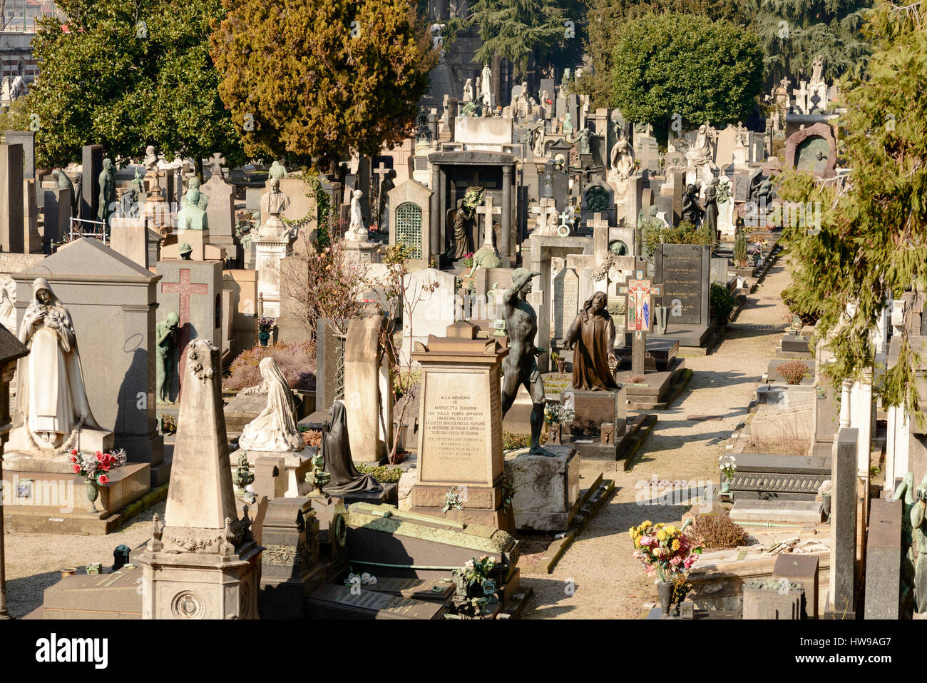 foreshortening of a crowd of statues and graveyards in field at large monumental Cemetery in town, shot in bright late winter light  in Milan, Lombard Stock Photo