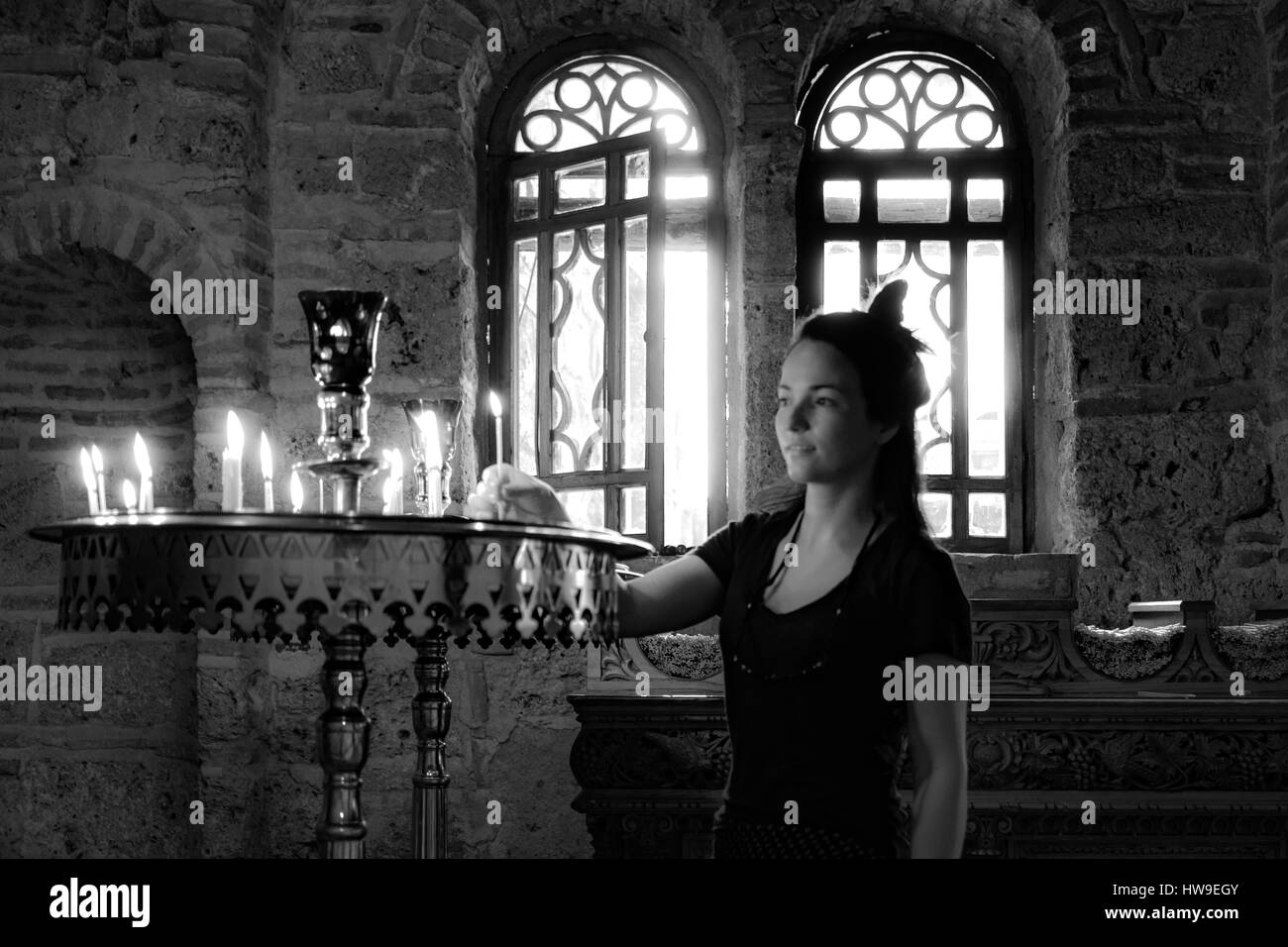 A woman lighting a candle in a greek monastery hires stock photography