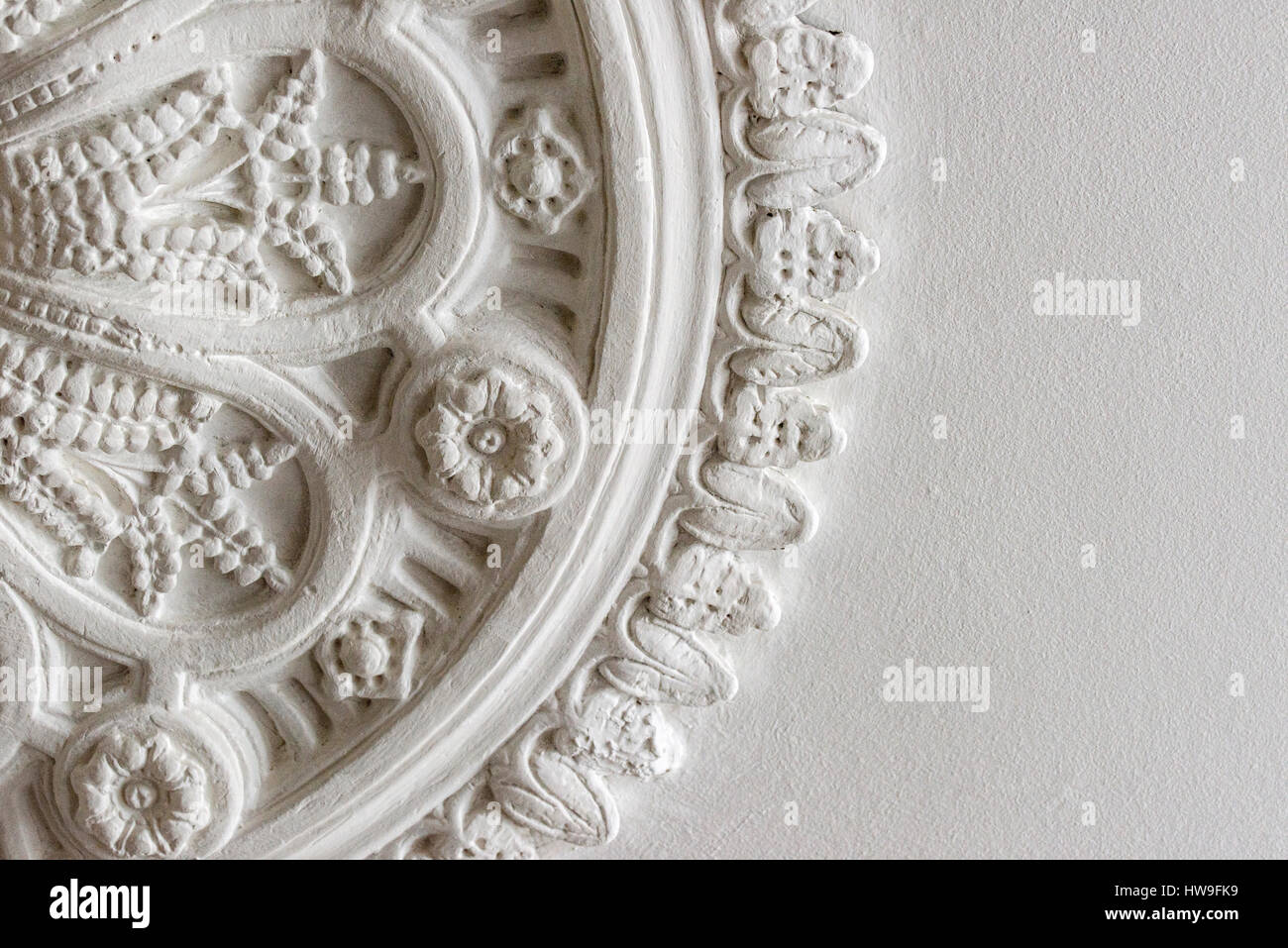 Close up photo of original Victorian white ceiling rose that found in a modern period proeprty. It is decorated with roses, leaves and petals. Stock Photo