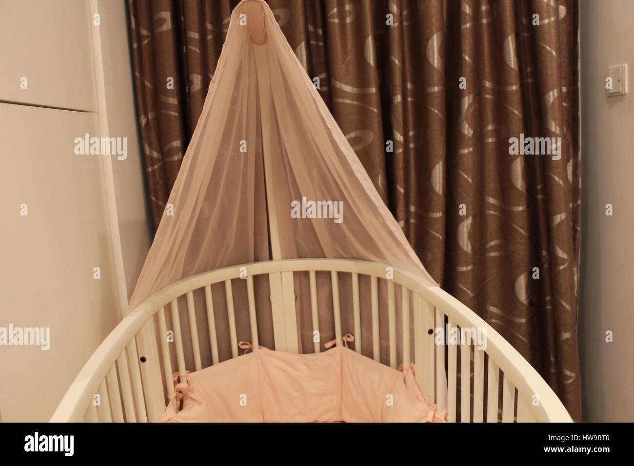 A gorgeous, really cute baby's crib with pink bedding in it Stock Photo