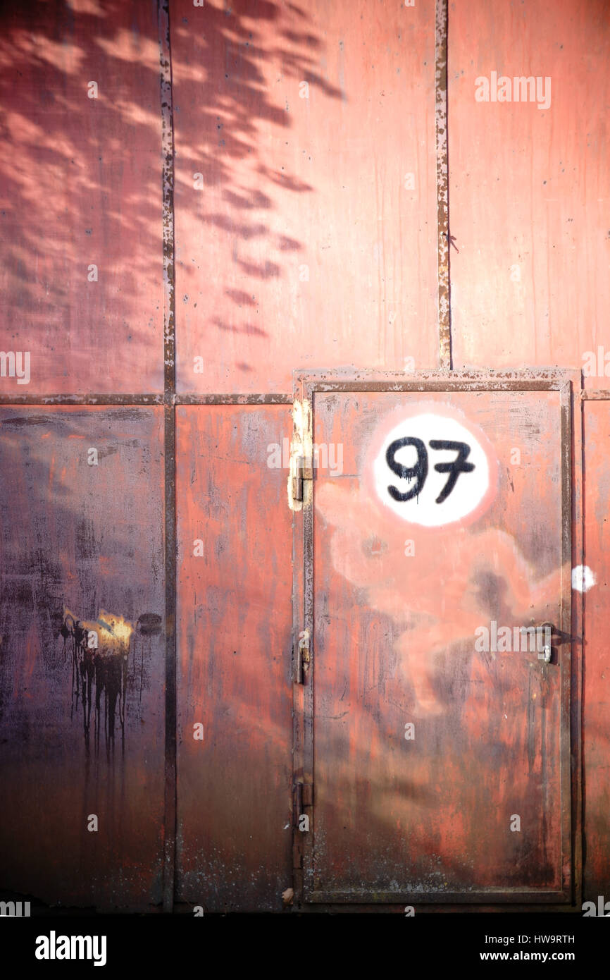 A rusted iron gate with a door and a sign Stock Photo - Alamy