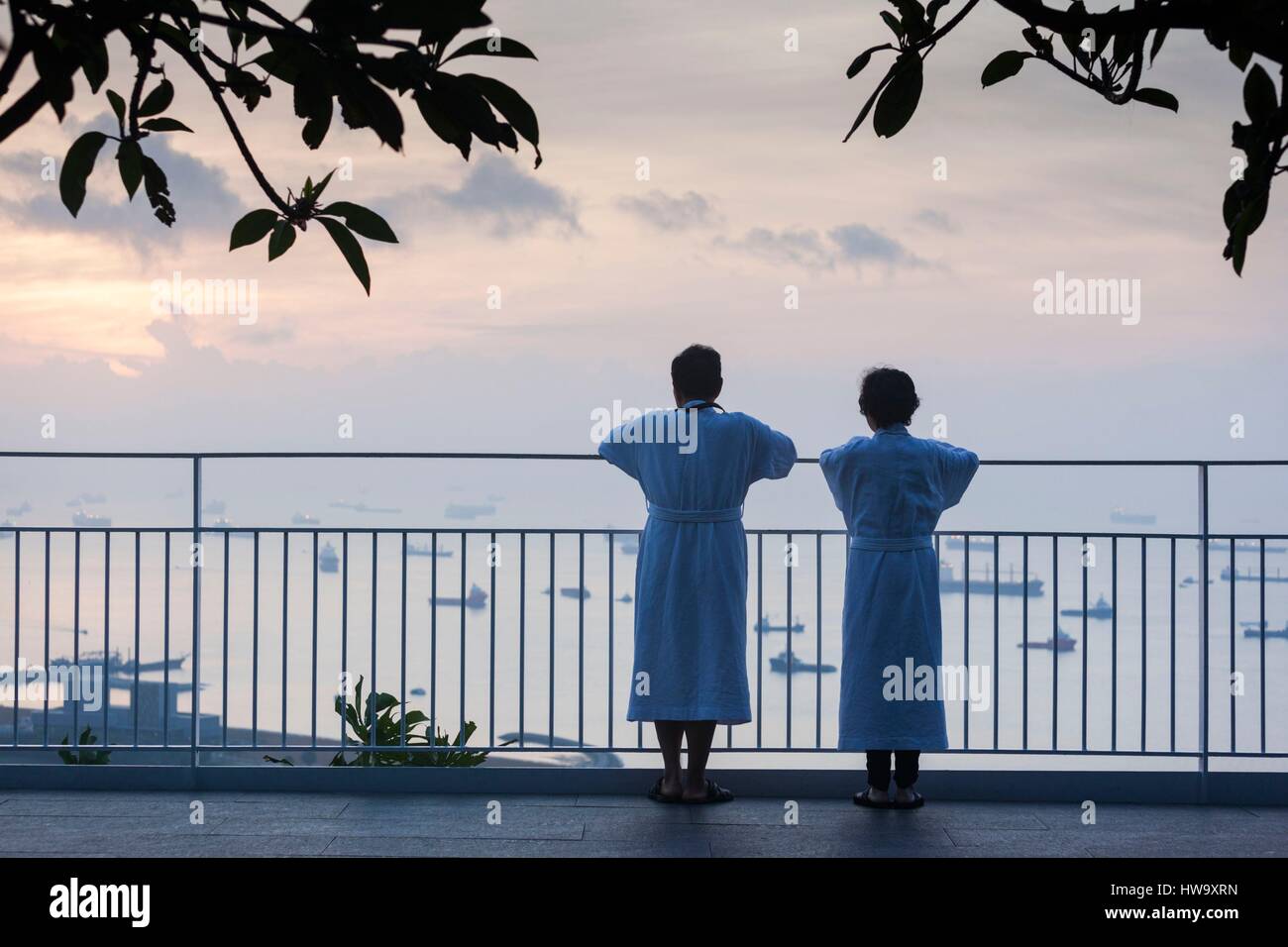 Singapore, Marina Bay Sands Hotel, couple overlooking Straits of Singapore, dawn Stock Photo
