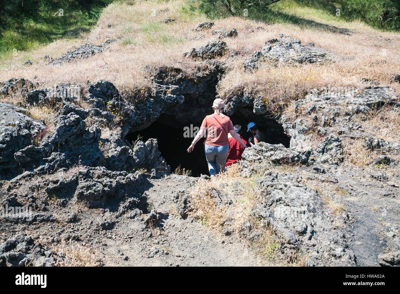 ETNA, ITALY - JULY 1, 2011 - tourists visit a cave in old crater of Etna volcano. Mount Etna is active volcano on the east coast of Sicily, the talles Stock Photo