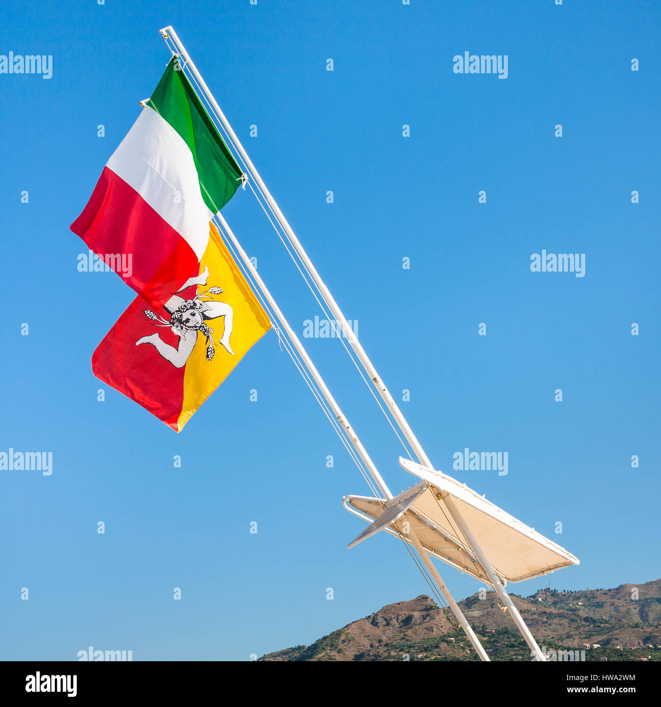 travel to Italy - Italian and Sicilian flags flutter by wind and blue sky in Sicily Stock Photo