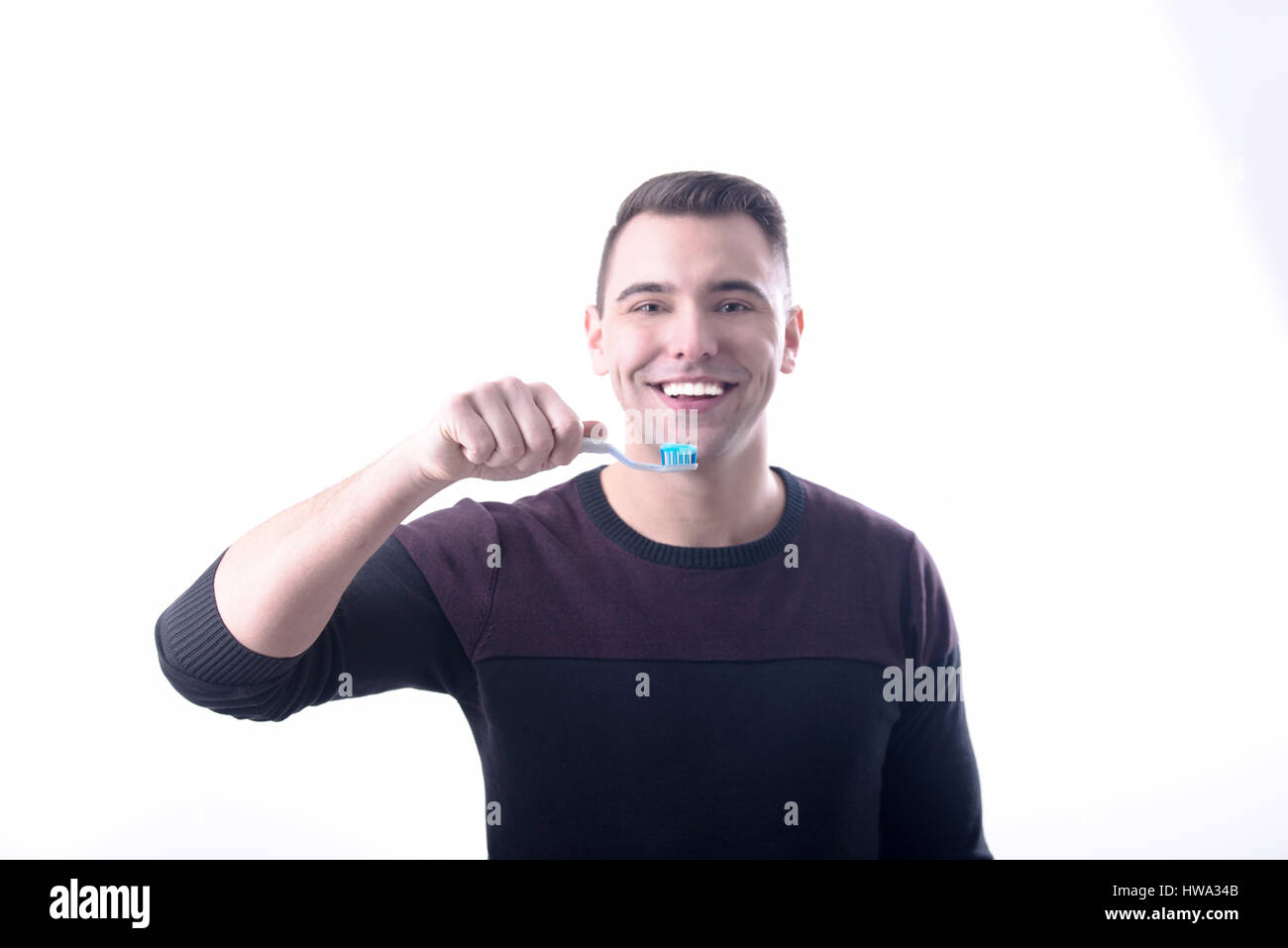 Young cheerful man with toothy smile holding a toothbrush.  White background,studioshot Stock Photo