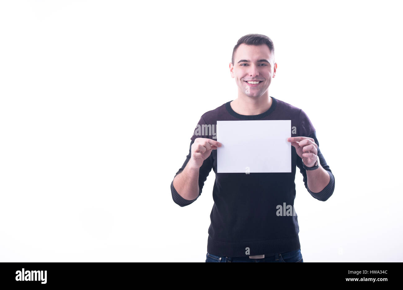Young cheerful man holding a paper horizontally on white background Stock Photo