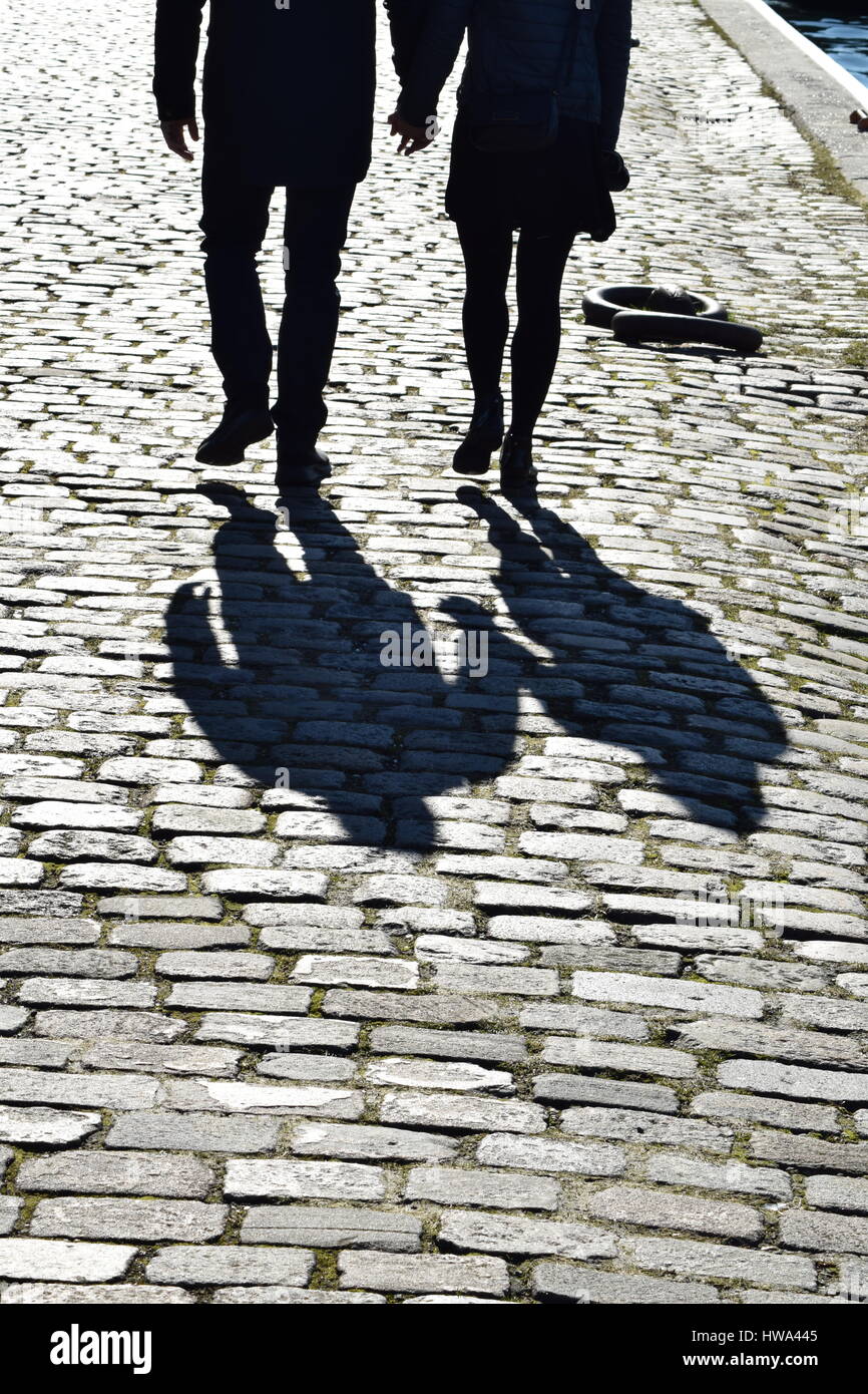 Man and woman holding hands while walking on cobble stones at Copenhagen harbor Stock Photo