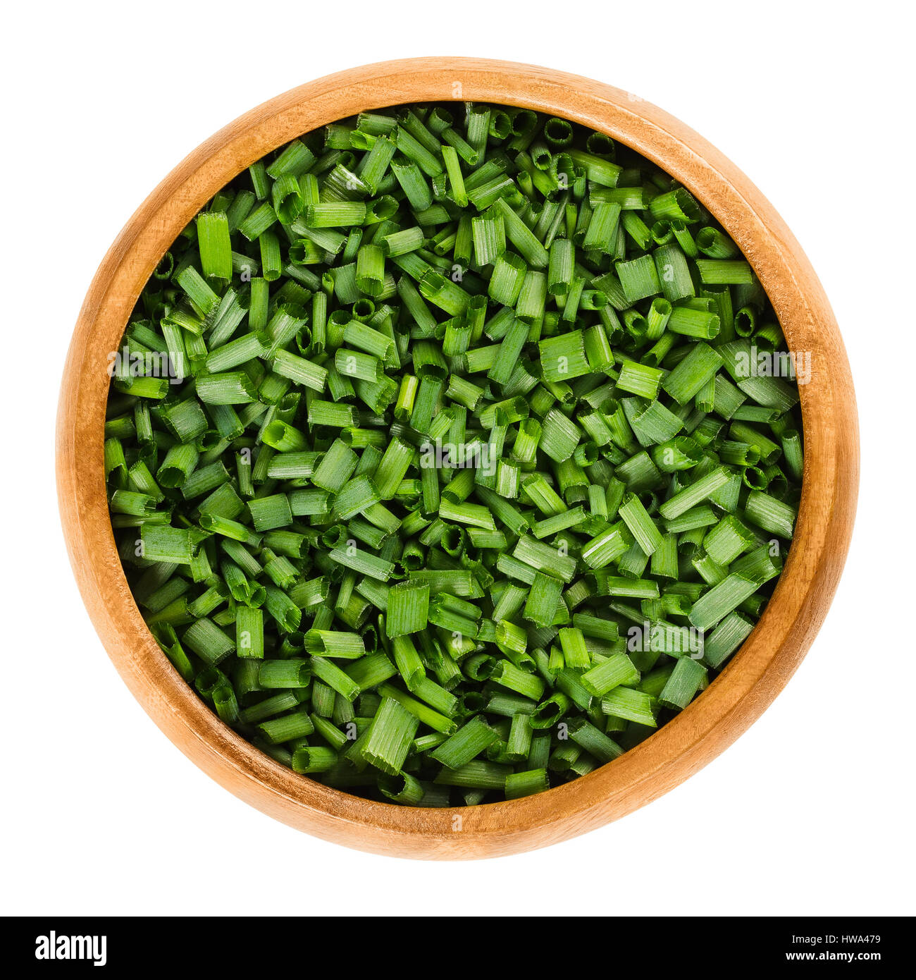 Chopped chives in wooden bowl. Fresh green edible herb of Allium schoenoprasum, used as an ingredient for fish, potatoes and soups. Stock Photo