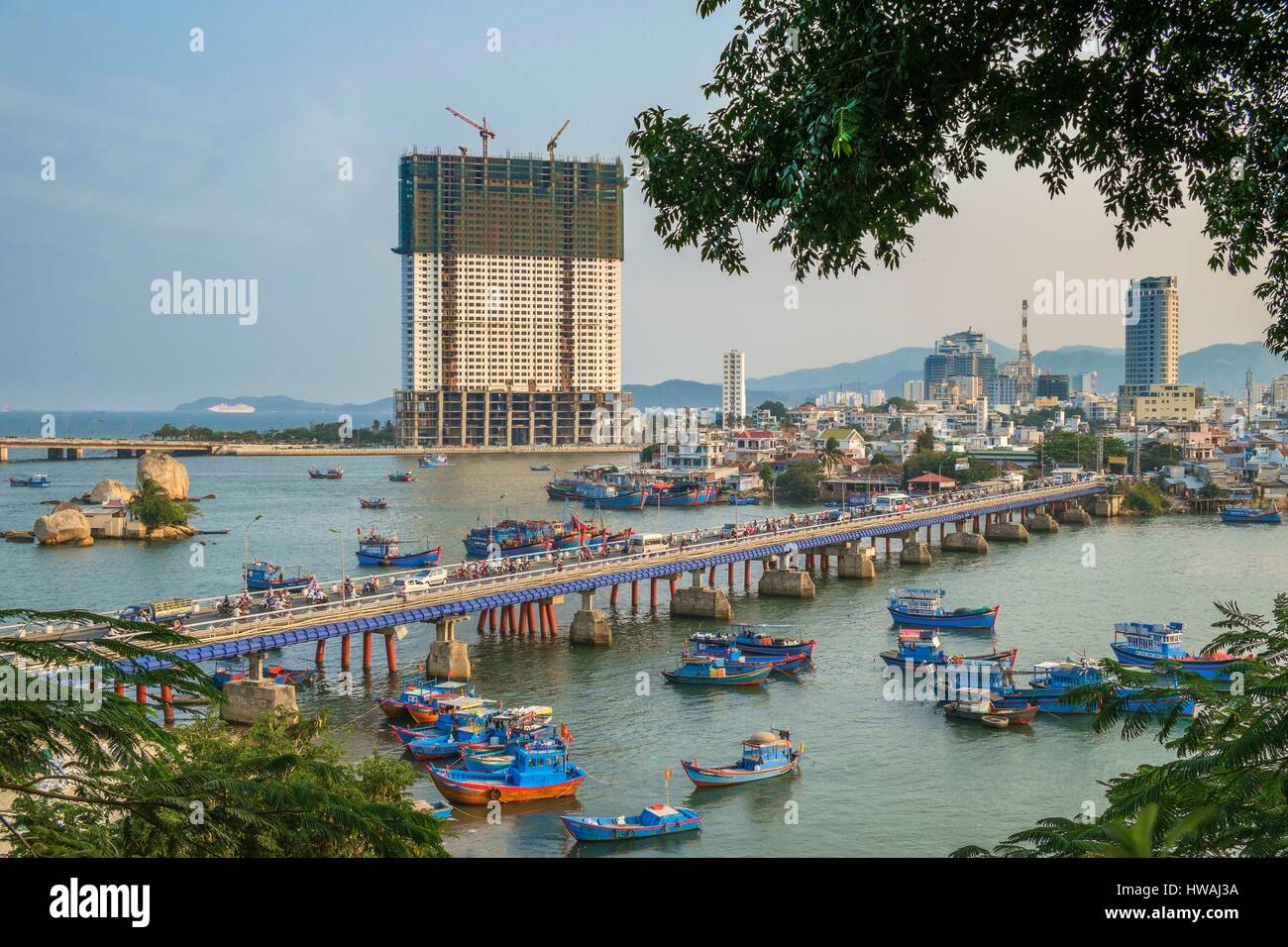 Vietnam, South Central Coast region, Khanh Hoa province, Nha Trang, fishing harbour, Xom Bong bridge and the 48 storeys Muong Thanh hotel under constr Stock Photo