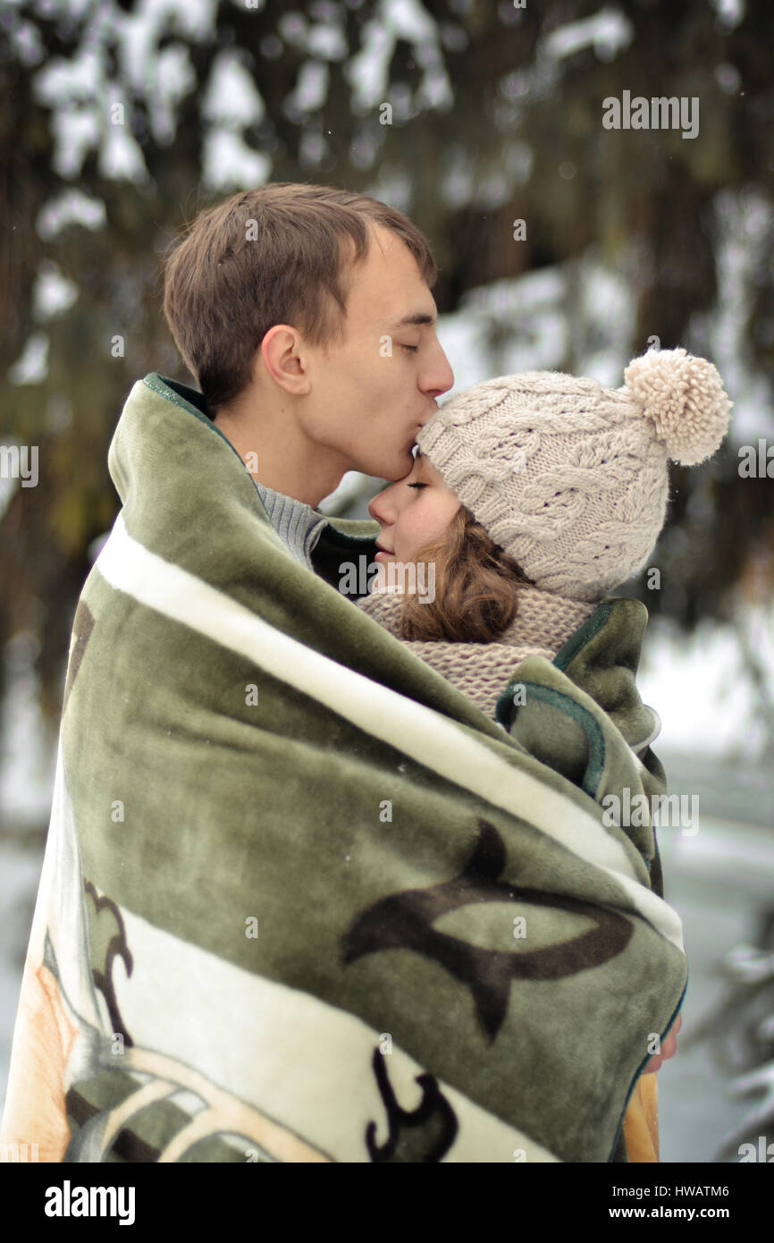Happy man kissing his beautiful girl on the forehead and covers her blanket. A handsome man kiss on the forehead her beloved, beautiful, pretty girl w Stock Photo