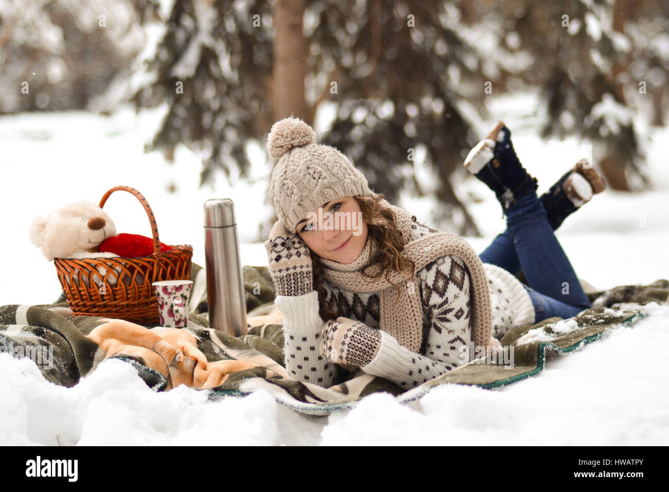 Beautiful,cute,happy,light girl sitting on a blanket in the winter in the cold,snow,fosest,forest and drinking cup of warm tea,background,little,decem Stock Photo