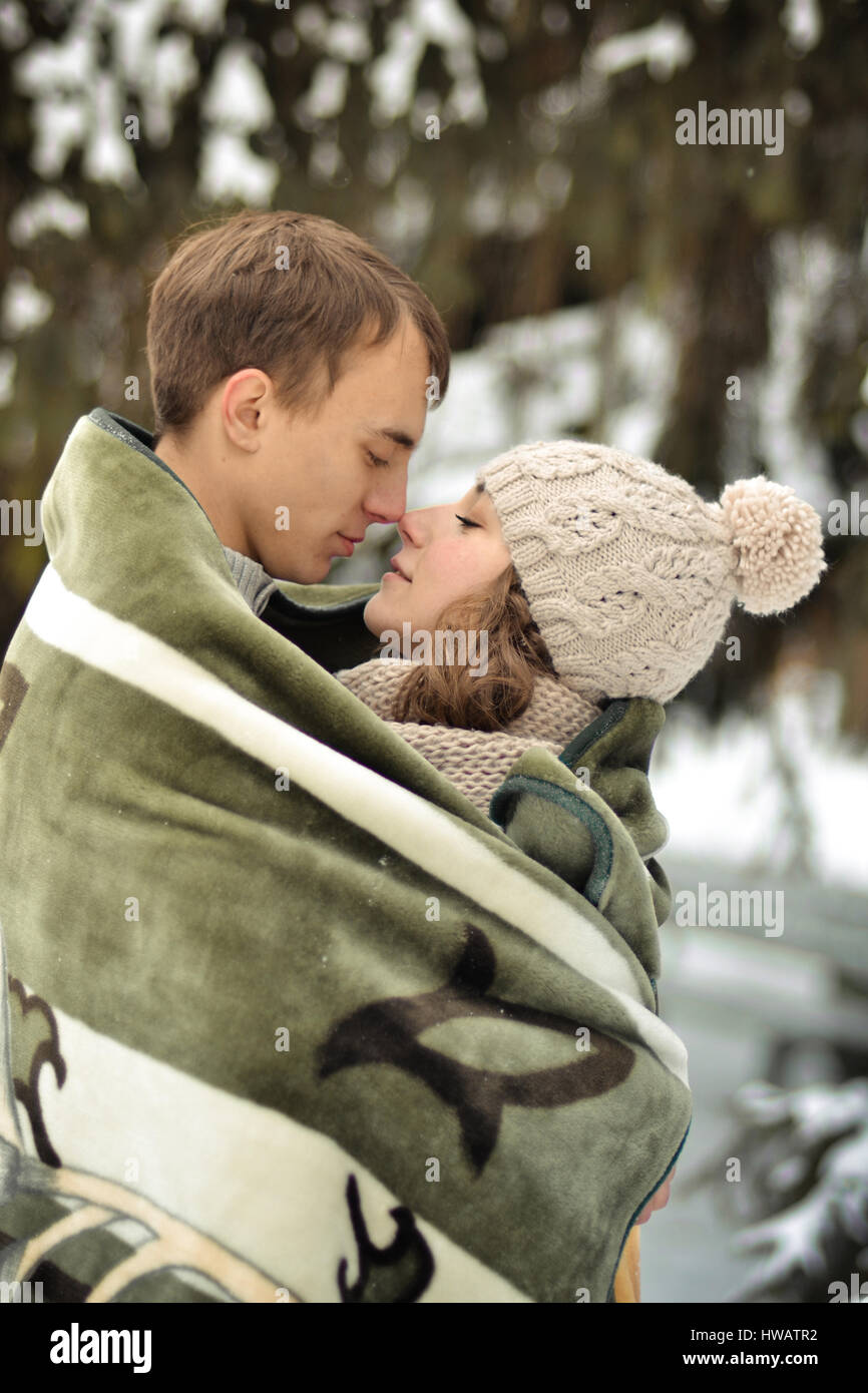 Handsome man kiss on the forehead her beloved, beautiful, pretty, attractive girl with sweater, mittens, winter, cold, snow forest, hut, love, happy,  Stock Photo