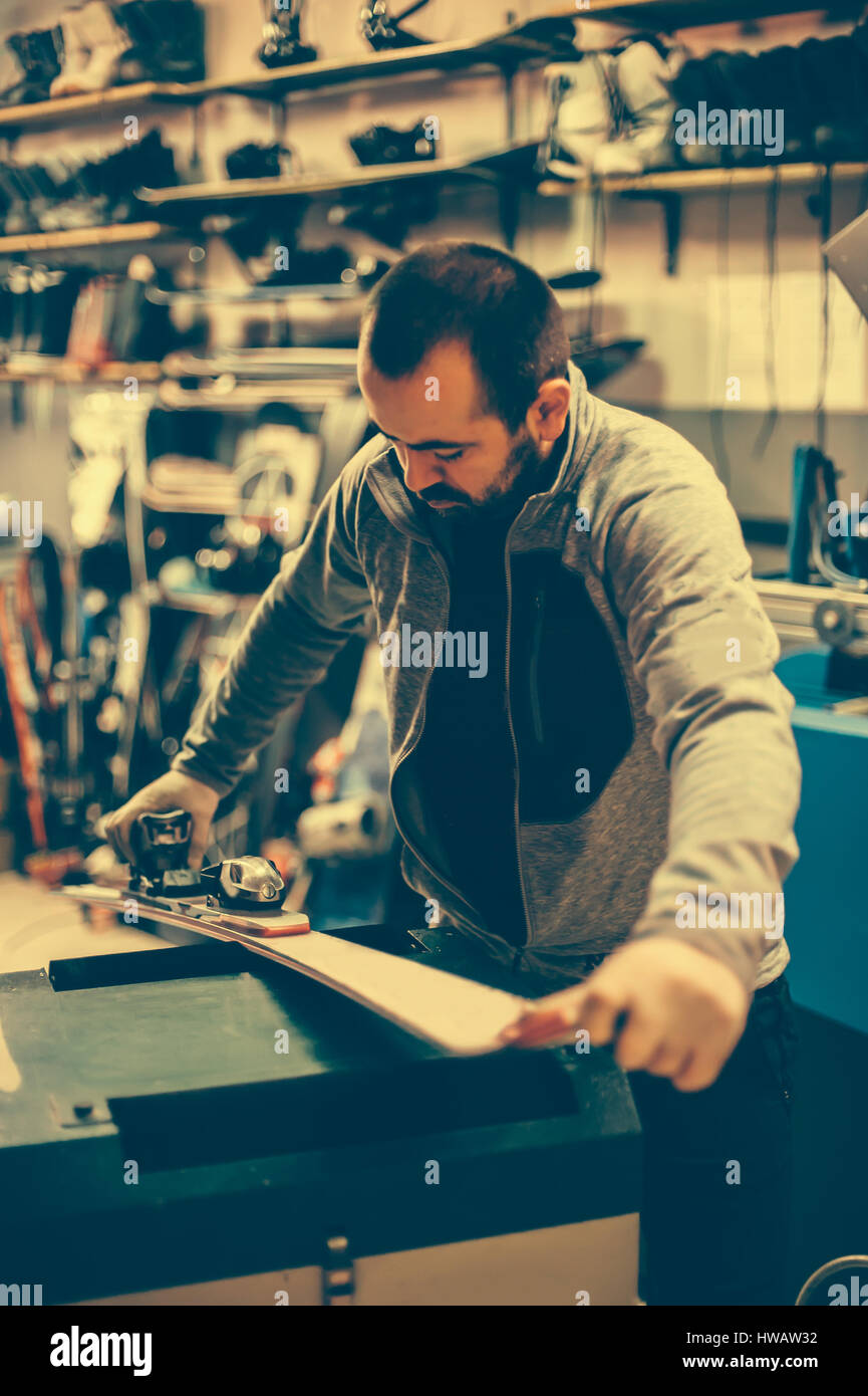 Ski tuning and reapair. Winter shop worker doing base repair. Rental