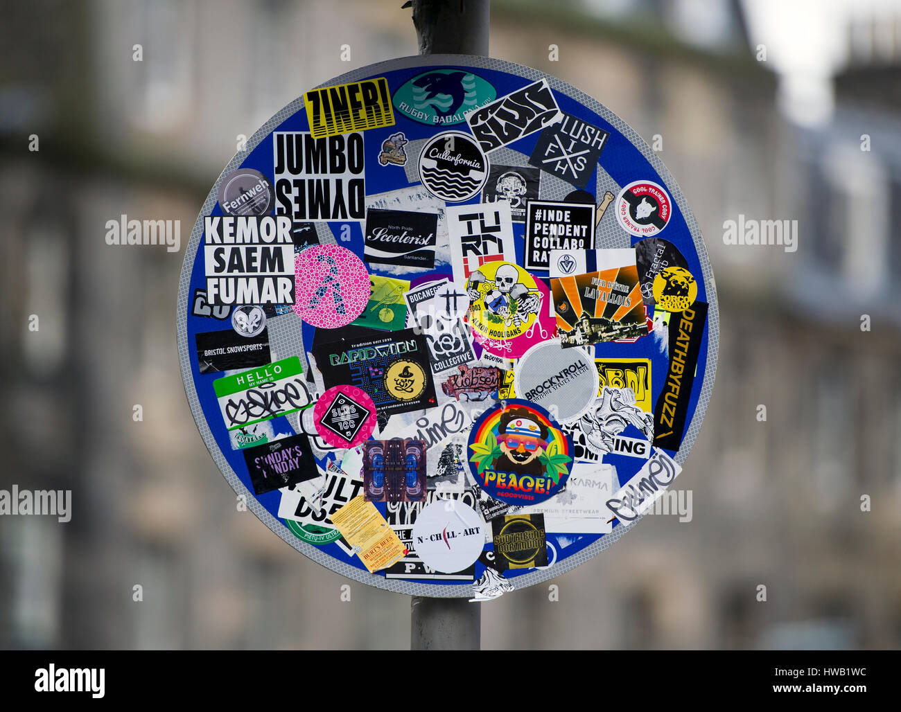 A road sign in Edinburgh covered in advertising flyers and stickers obscuring the traffic direction sign. Stock Photo