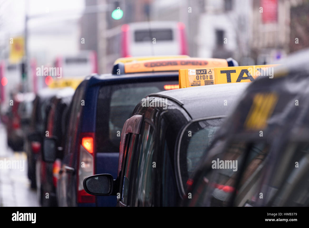 Black London-style taxis with yellow taxi roof signs lined up at a taxi rank outside Belfast City Hall Stock Photo