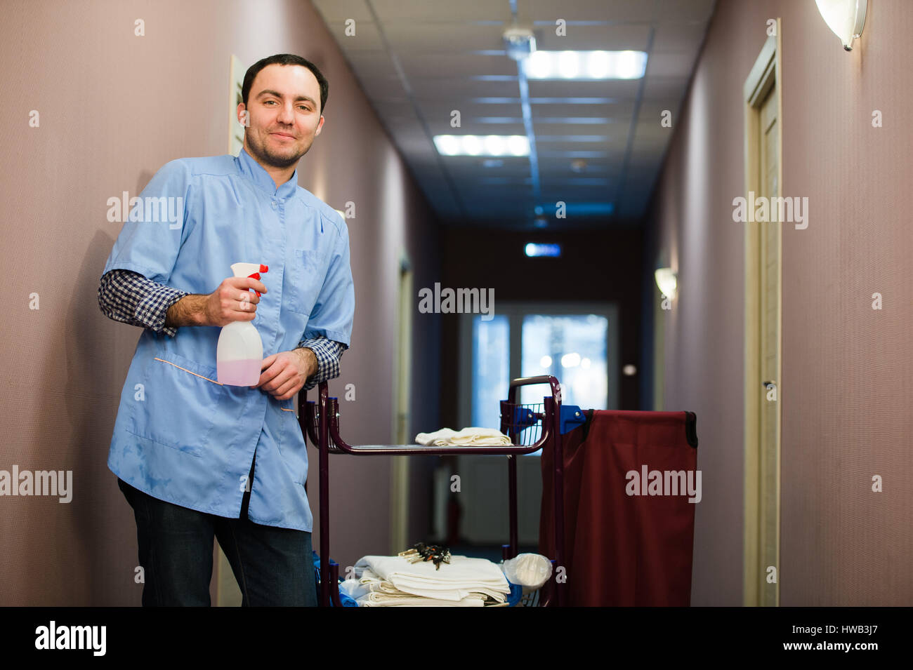 Man cleaning hotel hall wearing blue coat Stock Photo