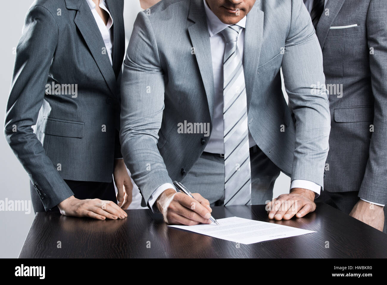 Businessman signing contract while his team is looking at him Stock ...