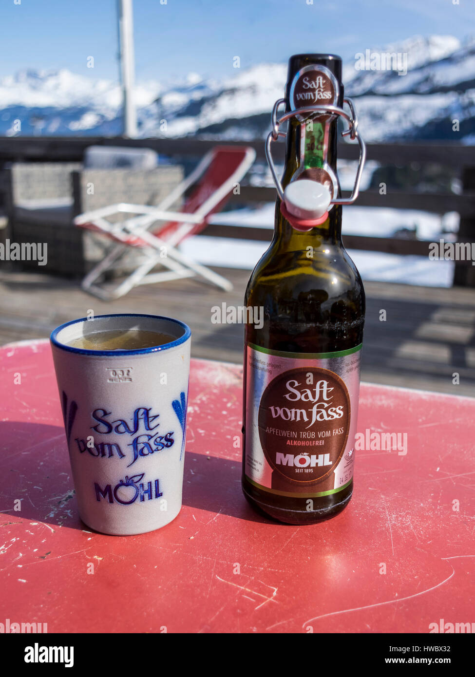 Bottle of non-alcoholic Möhl Apfelwein 'Saft vom Fass', a traditional Swiss cider, with a ceramic beaker. Alpine background. Stock Photo