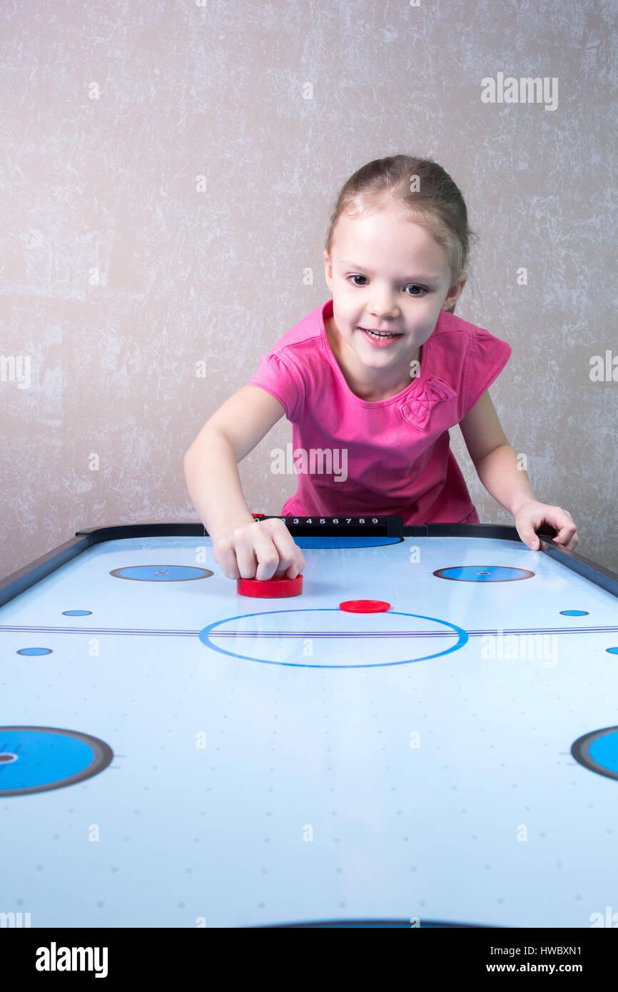 Little girl is playing in an air hockey Stock Photo