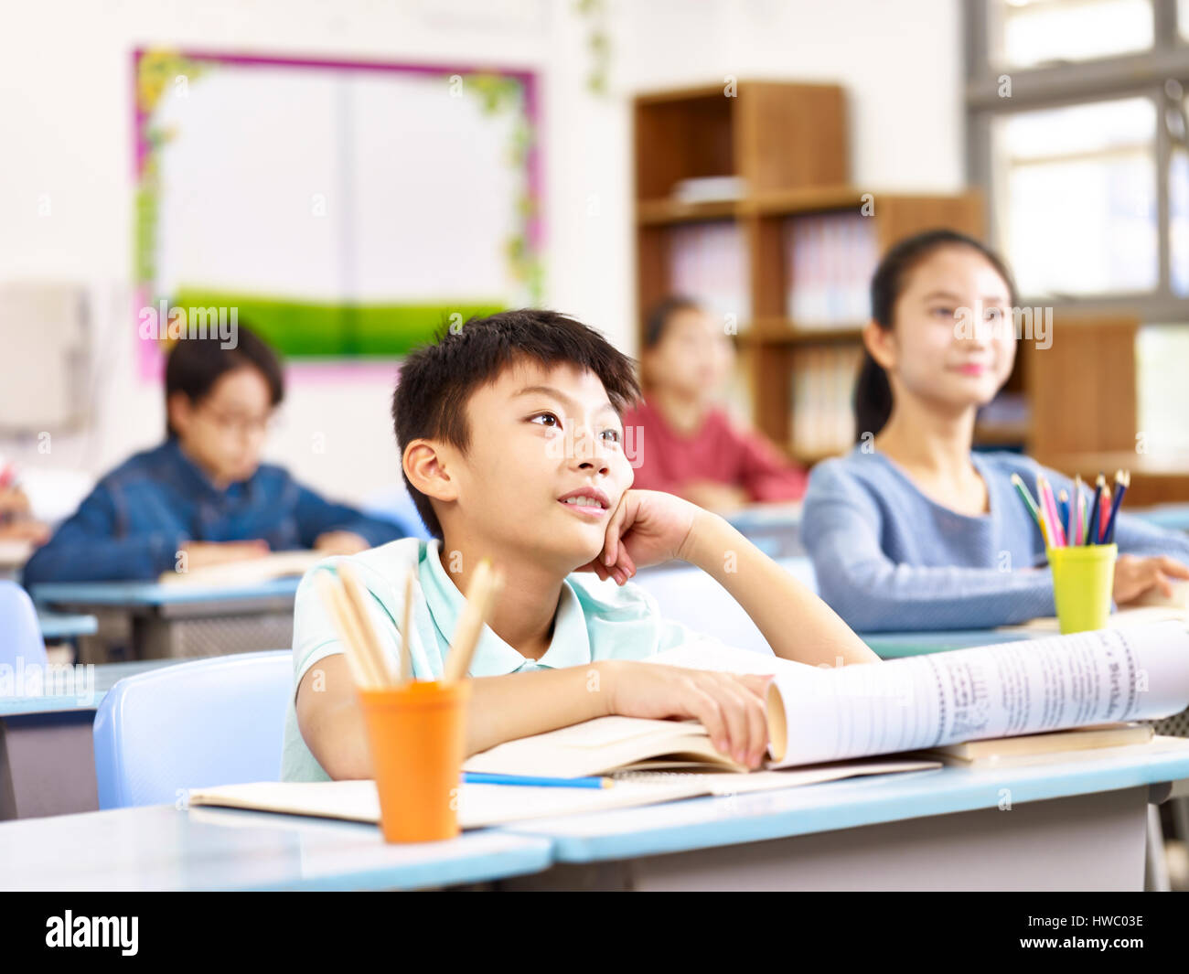 asian elementary school boy listening to teacher attentively in class. Stock Photo