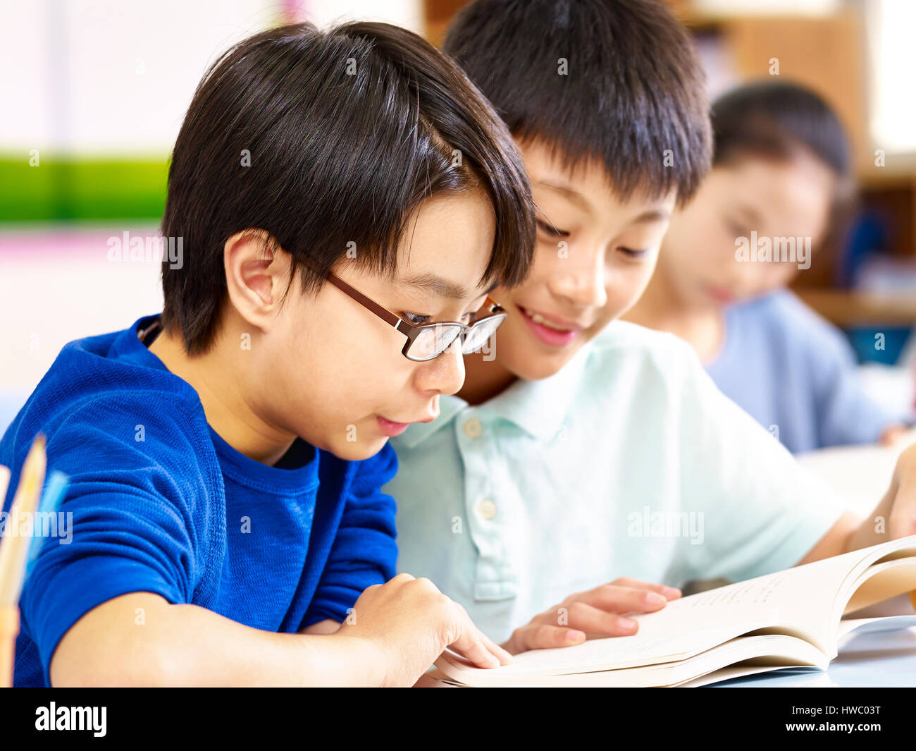 close-up of two asian elementary school pupil studying together in classroom. Stock Photo