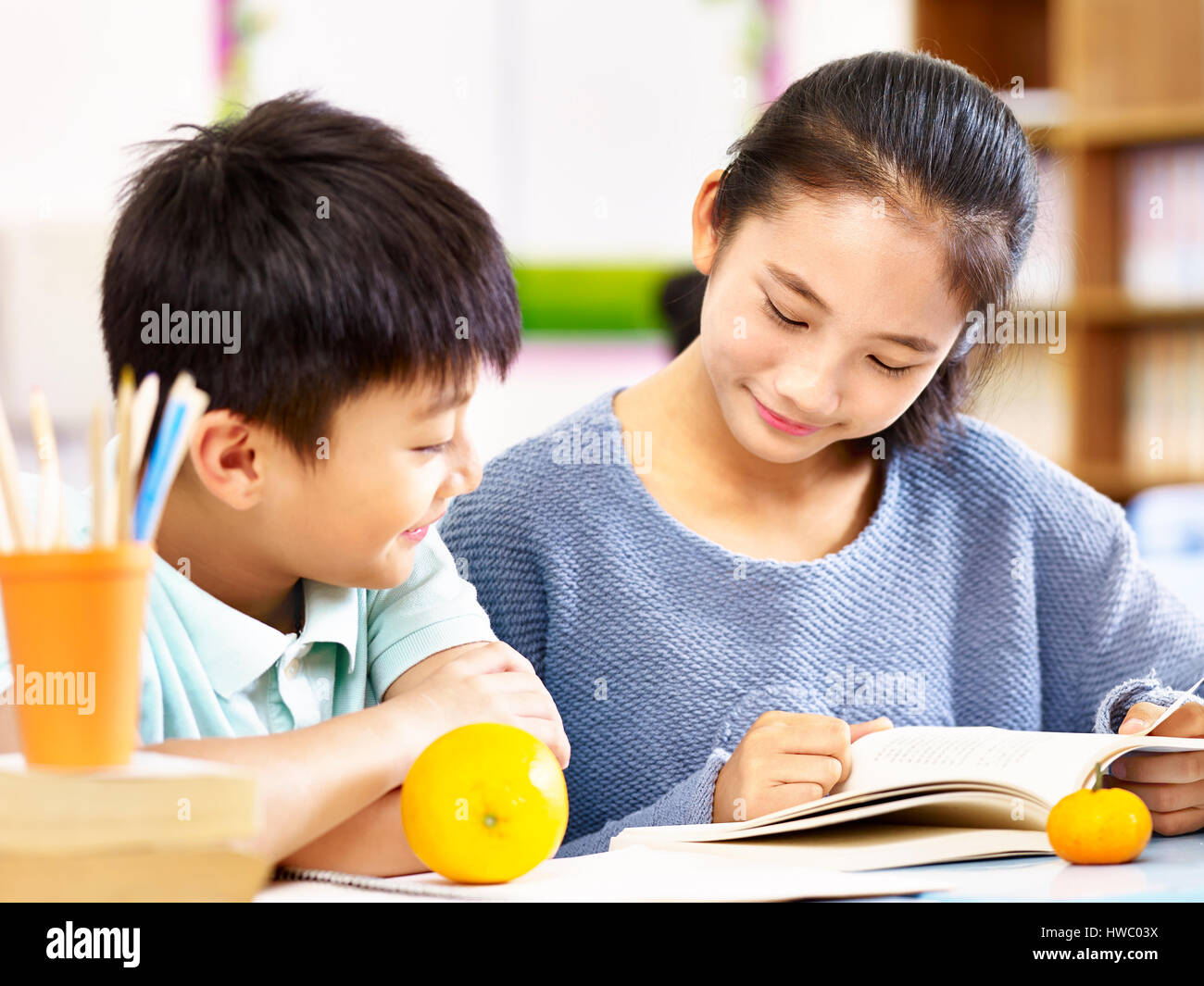 asian elementary school girl and schoolboy studying together in classroom. Stock Photo