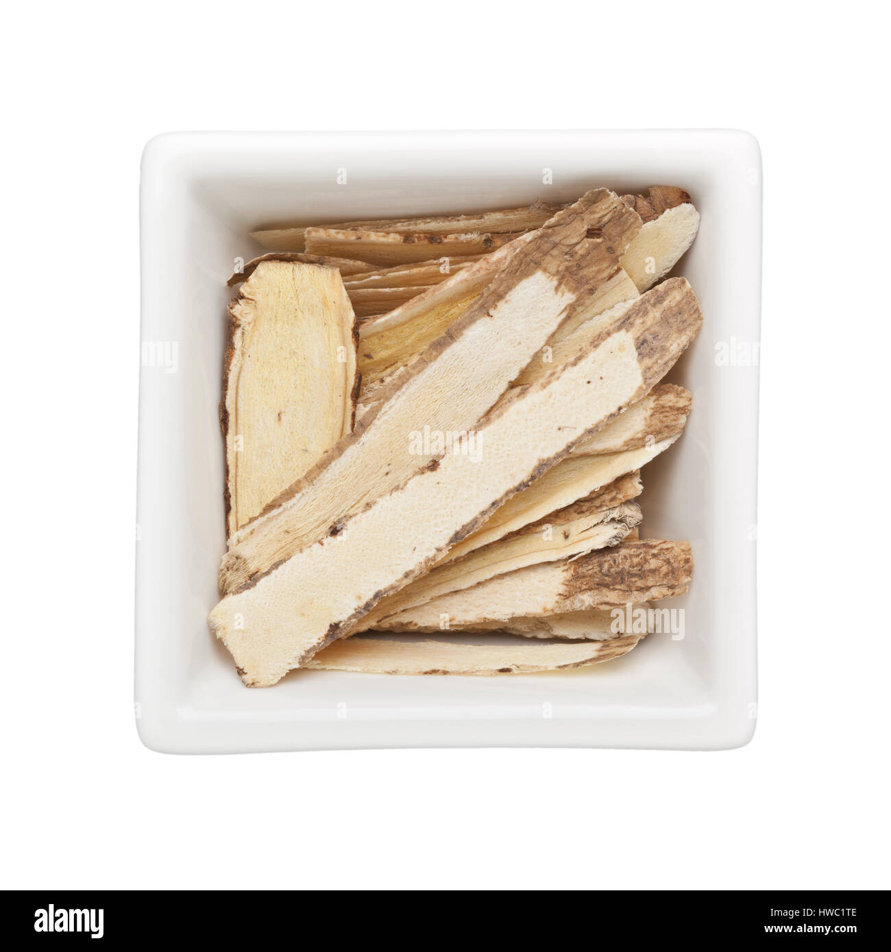 Traditional Chinese Medicine - Huang Qi (Astragalus root) in a square bowl isolated on white background Stock Photo